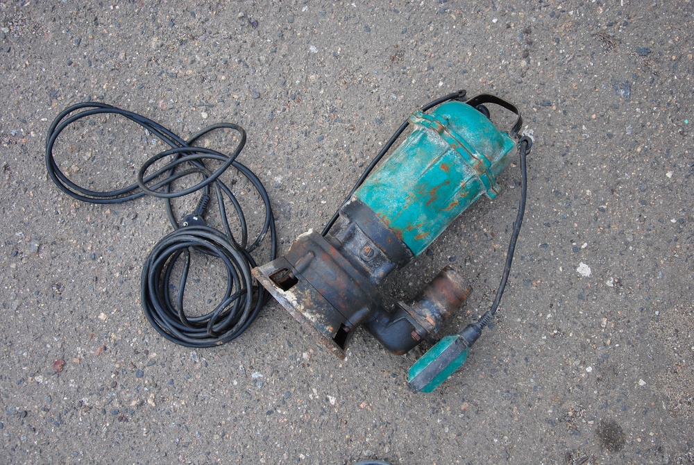 Close-up of a residential grinder pump motor jammed with fibrous flushable wipes, illustrating plumbing damage and the need for professional drain cleaning services.